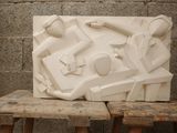a white sculpture on a wooden bench in front of a brick wall