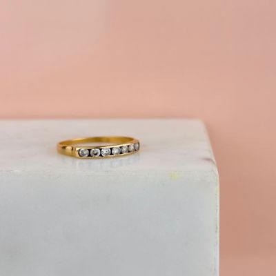 un gros plan d'une bague en or sertie de trois diamants, posée sur un bloc de marbre