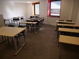 Il y a beaucoup de tables et de chaises dans cette salle de classe vide.