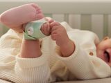 un bébé allongé dans un berceau, avec une tétine accrochée à son bras