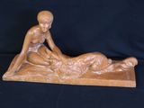 statue of a woman laying on a man ' s back on a black background