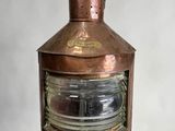 un grand luminaire en cuivre posé sur un socle en bois