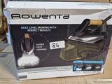 La boîte d'un fer à repasser à vapeur est posée sur un carton
