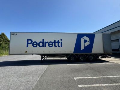 un gros semi-remorque garé devant un immeuble