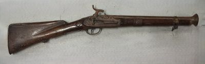 un vieux fusil exposé sur une surface blanche