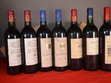 six bottles of red wine are lined up on a red table