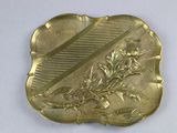 brass plate with a design of flowers and leaves on a white surface