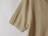 beige polo shirt hanging on a hanger on a white wall