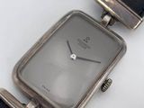 a silver watch sitting on a black leather strap