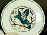 a plate with a bird painted on it next to bowls and cups