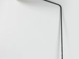 une lampe noire et blanche accrochée au mur, à côté d'un mur blanc