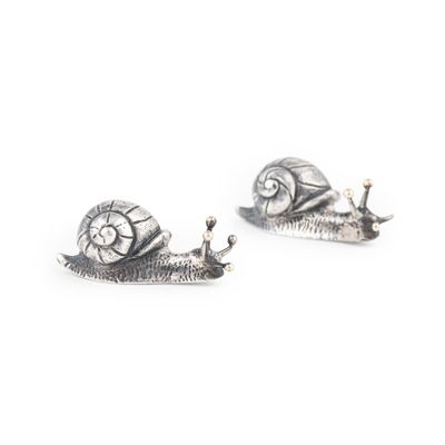 une paire de boucles d'oreilles en forme d'escargot en argent sur fond blanc