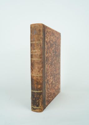 un vieux livre posé sur une table blanche à côté d'un mur blanc