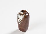 a brown vase sitting on a white surface with a black background