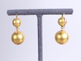 a pair of gold ball earrings on a stand