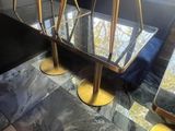 a glass table with gold legs on a marble floor