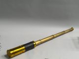 a gold telescope with a black handle on a white table