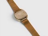 a close up of a gold watch on a white surface
