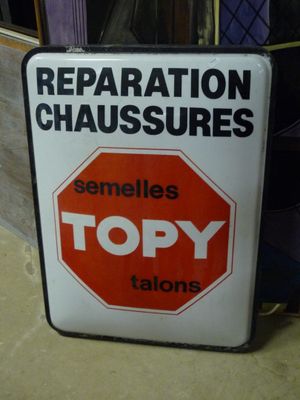 une enseigne indiquant « Réparation de chaussures » sur la façade d'un immeuble