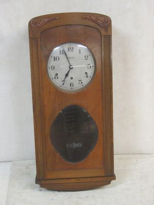 a clock that is sitting on the floor in front of a white wall