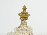 a small glass bottle with a gold top on a white surface