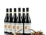 quatre bouteilles de vin rouge posées à côté d'un tas de brindilles