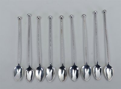 six cuillères en argent avec des chaînes qui pendent, posées sur une table