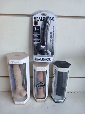 trois types différents de sextoys, rangés dans des boîtes posées sur une table