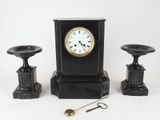 une horloge noire posée à côté de deux tabourets