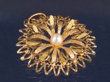 une broche en or ornée d'une perle au centre