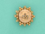 un gros plan d'une broche en or et perles sur fond turquoise