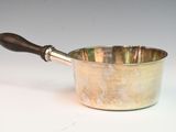 a small metal pot with a wooden handle on a white surface