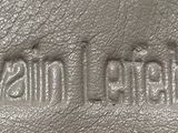 the logo on the back of a brown leather bag