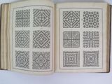 an open book with black and white designs on it sitting on a table