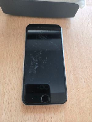 Un iPhone est posé sur une table en bois, à côté d'une boîte.