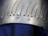 a close up of a silver cuff with a blue shirt underneath it