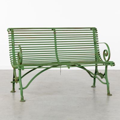 an old green bench sitting in a cement floor next to a white wall