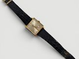 gros plan d'une montre sur une surface blanche avec un bracelet noir