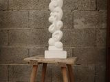 a white sculpture sitting on a small table in front of a brick wall