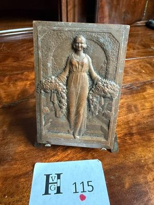 une photo d'une plaque posée sur une table, sur laquelle figure le portrait d'une femme