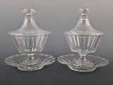 une paire de salières et poivrières en verre transparent posées sur une soucoupe