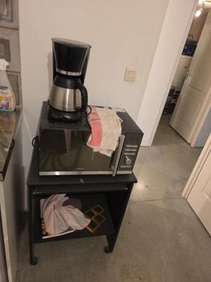 une cafetière posée sur une petite table noire dans une cuisine