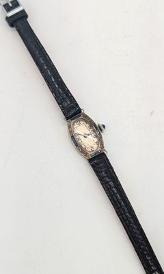 gros plan d'une montre sur une surface blanche avec un bracelet noir