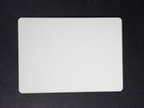 a close up of a white mouse pad on a black surface