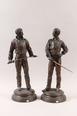 pair of bronze figurines of a man and a woman holding swords