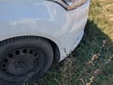 a white car that has been damaged and is sitting in the grass