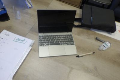 un ordinateur portable posé sur un bureau, à côté d'un sac