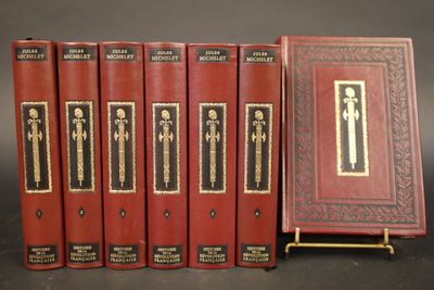 six livres rouges sont alignés sur une surface noire