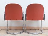 pair of red chairs sitting on top of a tiled floor
