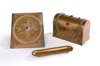 une boîte dorée ornée de pierres bleues, à côté d'une boîte contenant un stylo